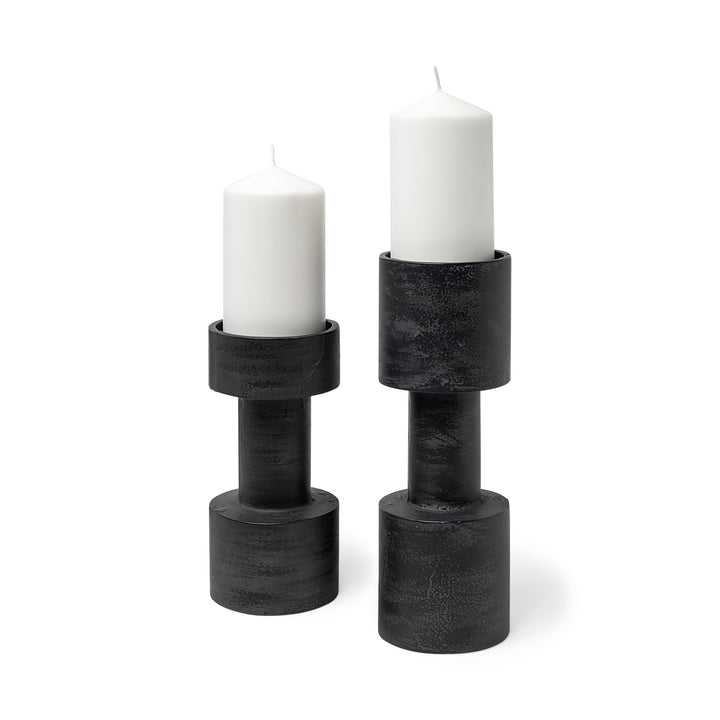 Two black candle holders with white candles on a white background