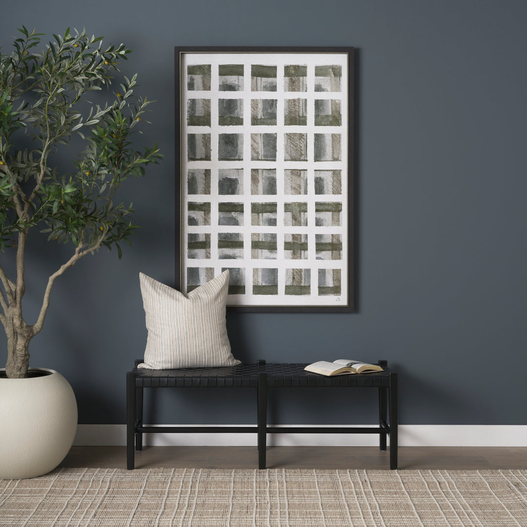 Nest living room with a plant, bench, and framed artwork on a dark gray wall.