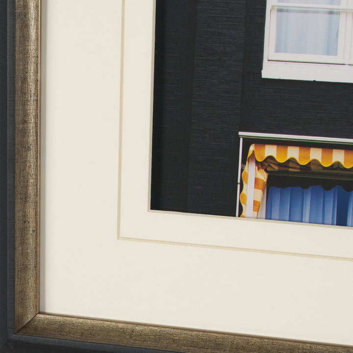 Framed artwork of a building with a striped awning