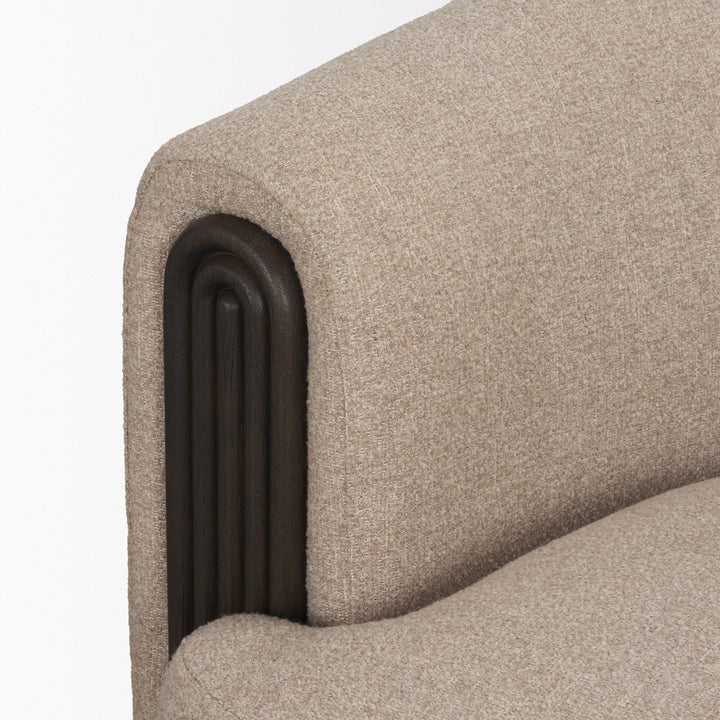 Close-up of a textured beige upholstered chair with a dark wooden armrest 