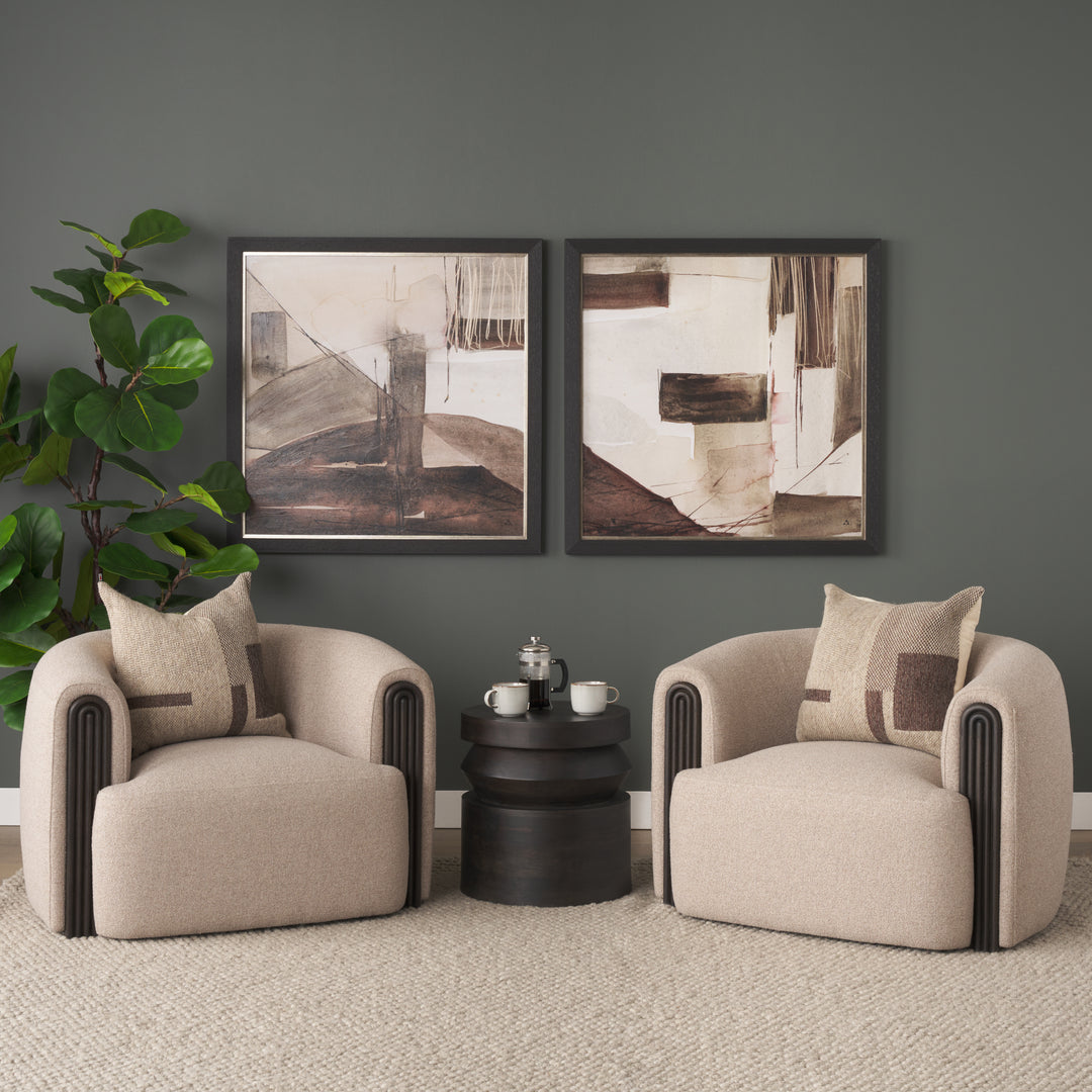 Two beige armchairs with a small black table and abstract art on a gray wall.