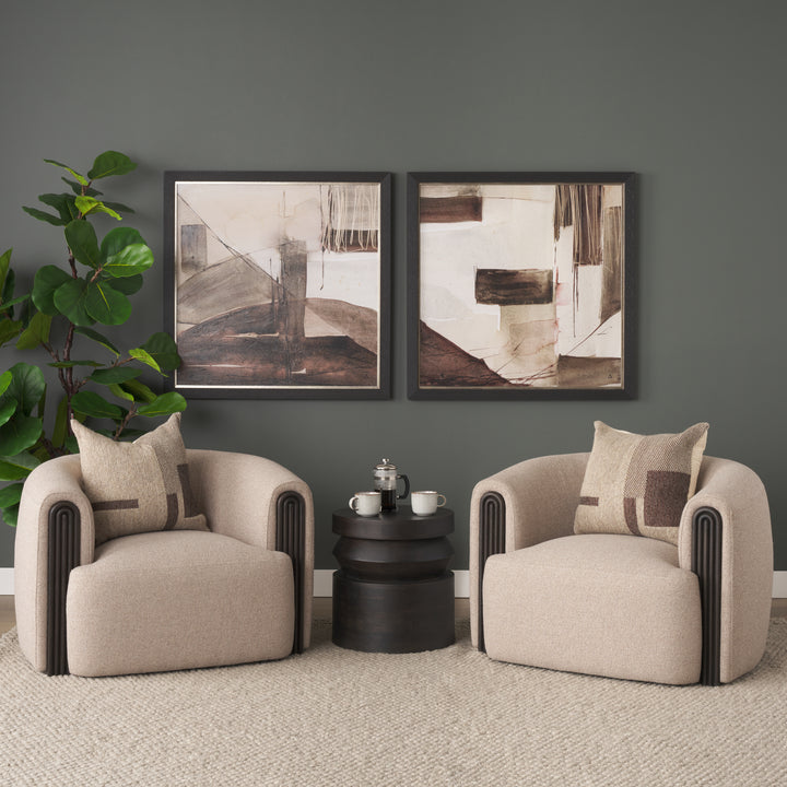 Two beige armchairs with a small black table and abstract art on a gray wall.
