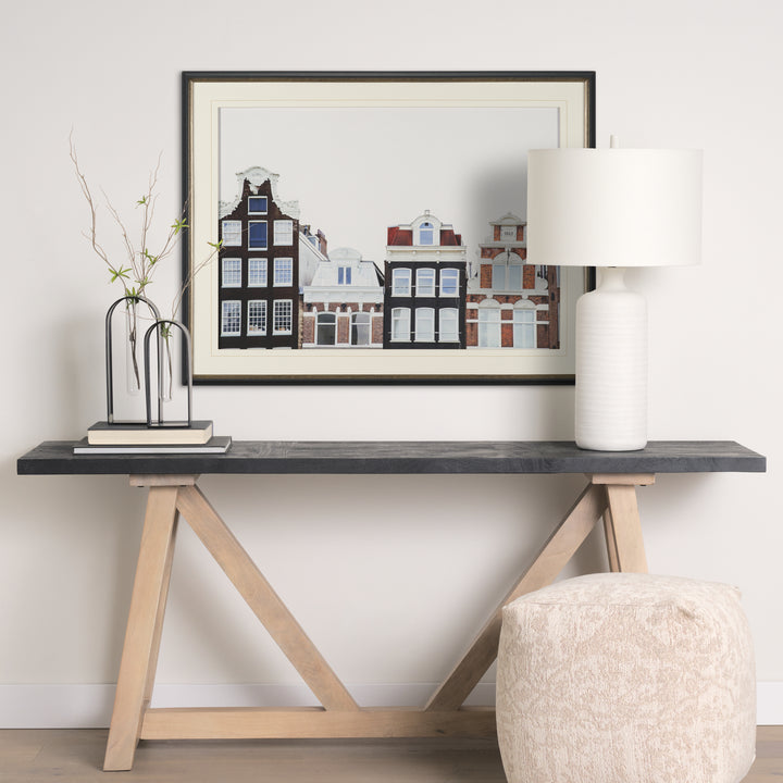 Modern console table with a lamp, vase, and framed artwork in a room.