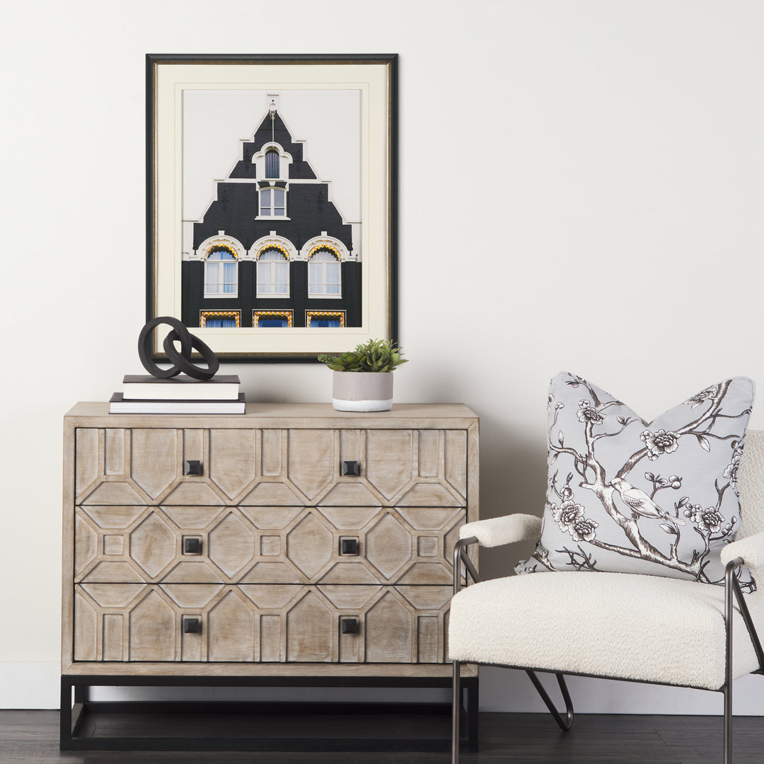 Decorative chest of drawers with a framed picture and chair in a room setting