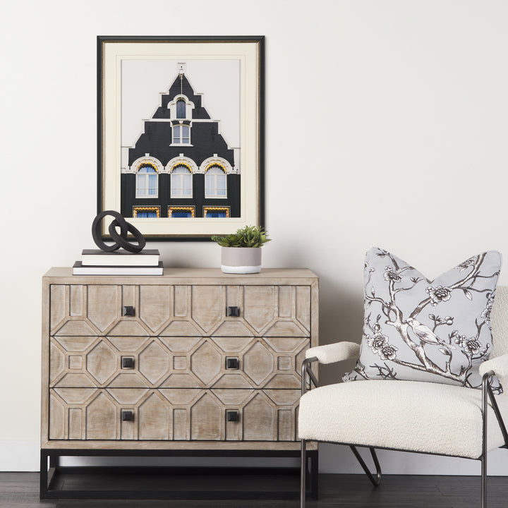 Decorative chest of drawers with a framed picture and chair in a room setting