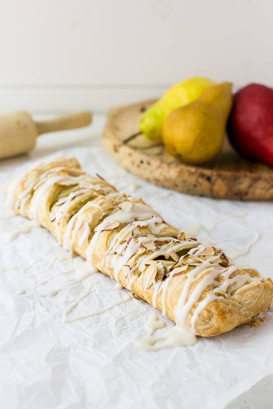 Pastry with icing on a white surface with pears in the background