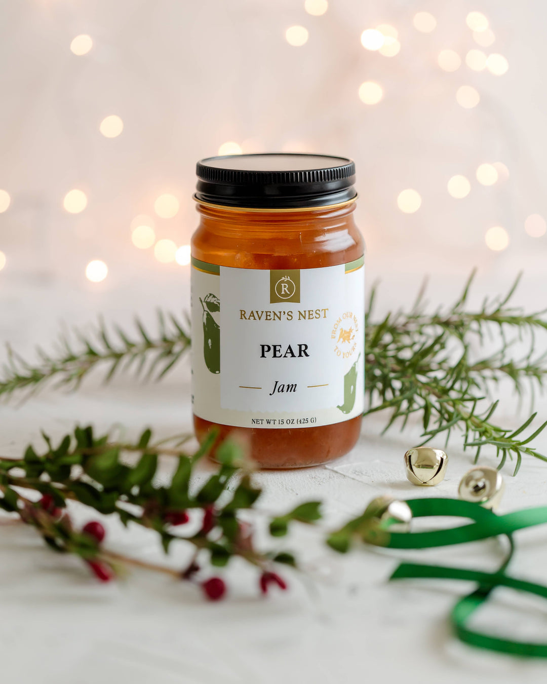 Jar of Raven's Nest Pear Jam with festive decorations on a light background