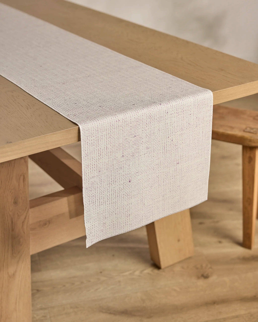 Beige table runner on a wooden table with a neutral background