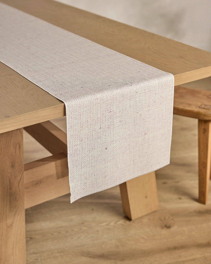 Beige table runner on a wooden table with a neutral background