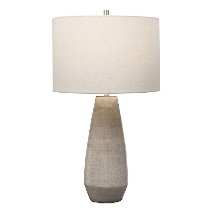 Simple yet stylish, this ceramic table lamp is finished in a crackled taupe-gray glaze with noticeable distressed details and antique brushed brass accents. The round hardback drum shade is a white linen fabric.