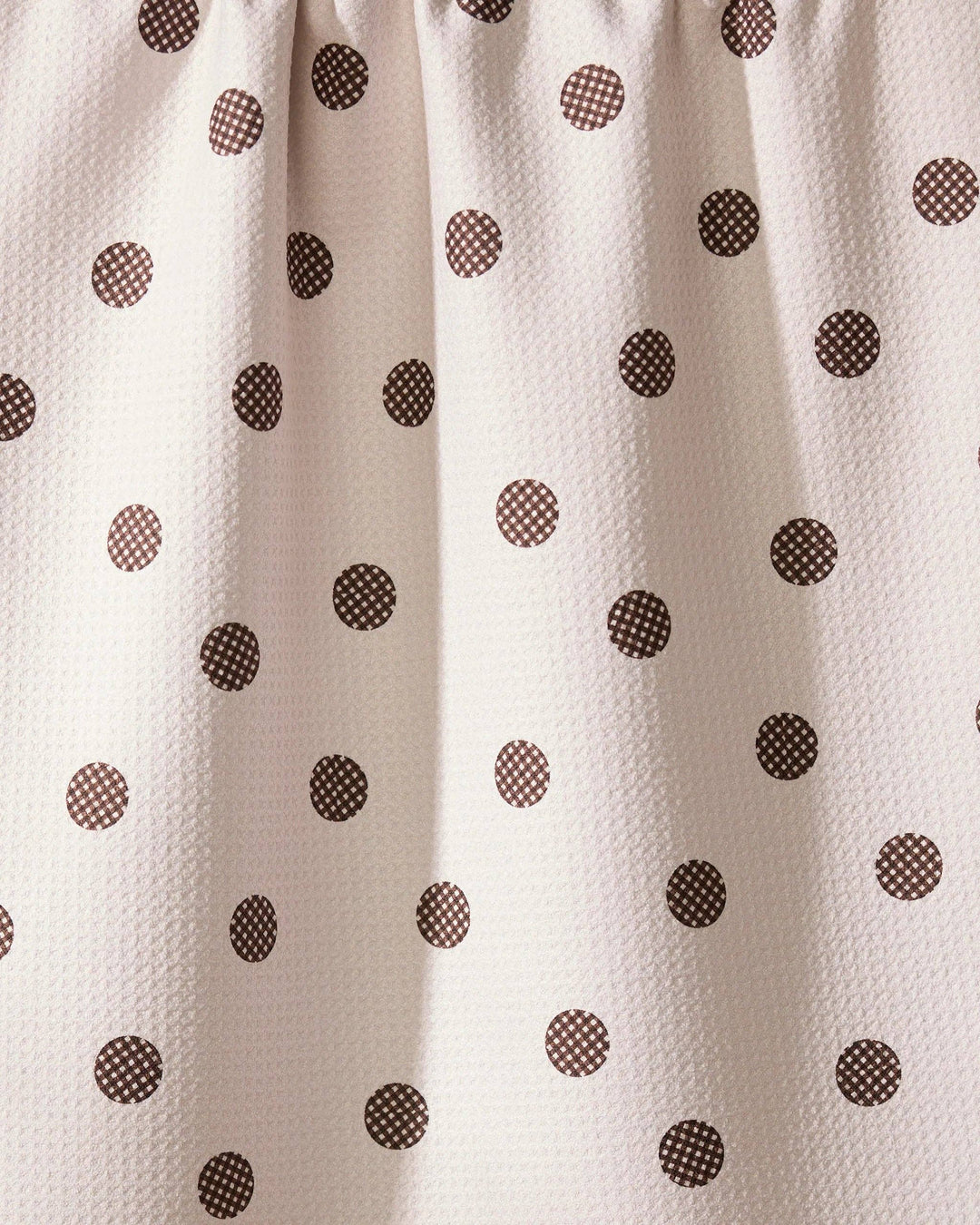 Close-up of a geometry towel with brown polka dots on a beige background
