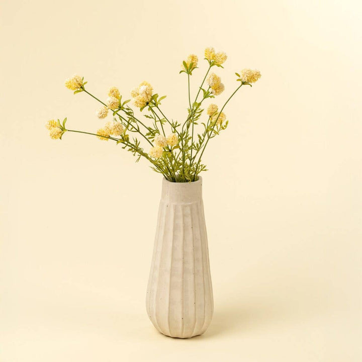 White vase with yellow floral greenery on a beige background