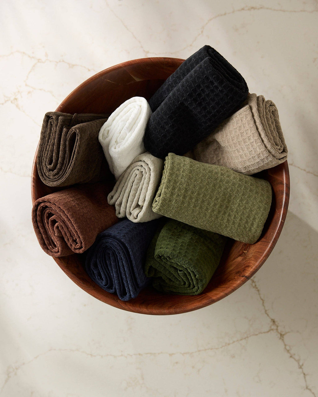 Wooden bowl filled with folded socks in various colors on a light background