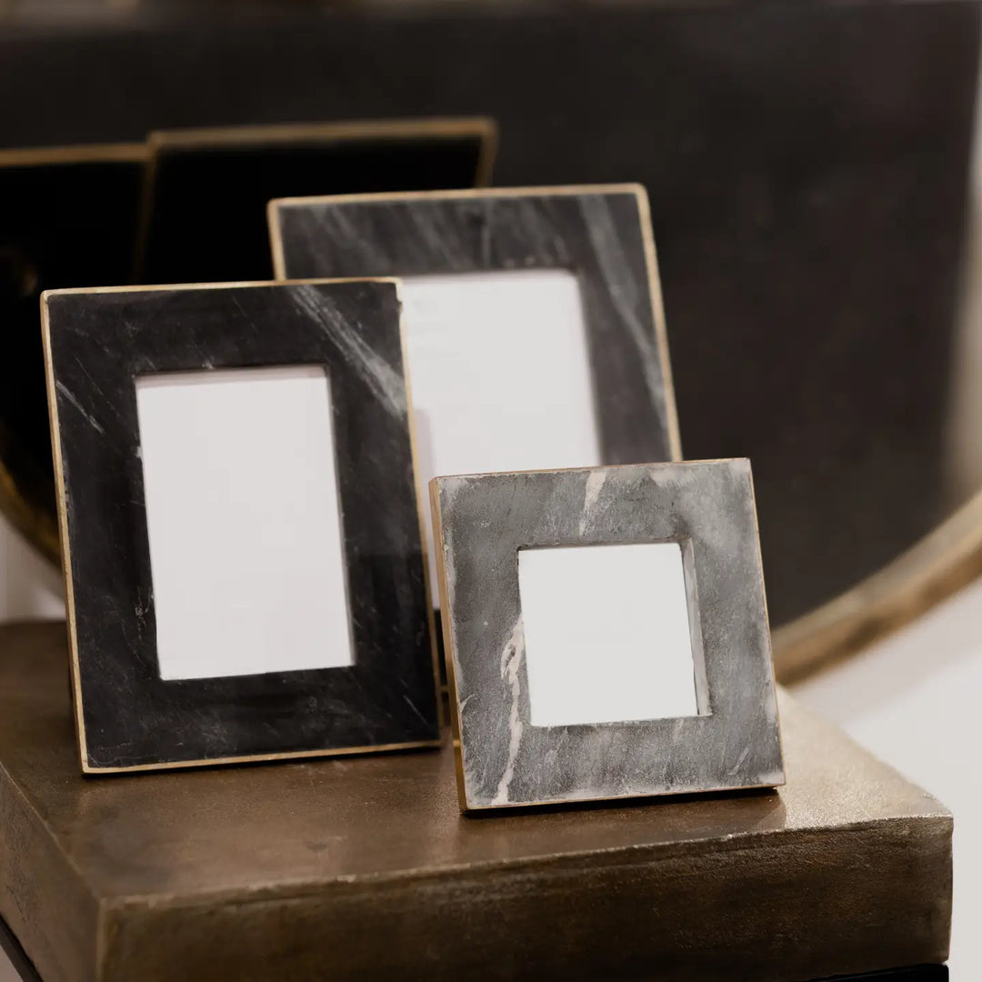 Three decorative black marble picture frames on a wooden surface 