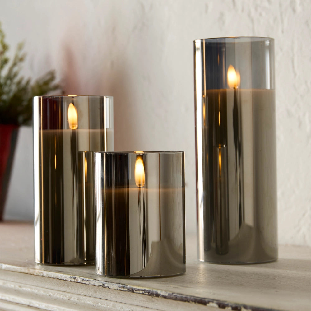 Set of three smoked glass candles on a wooden surface with a blurred background