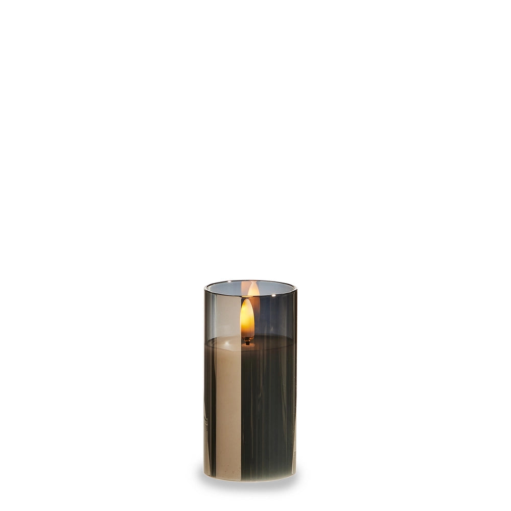 Smoked glass candle holder with a lit candle on a white background