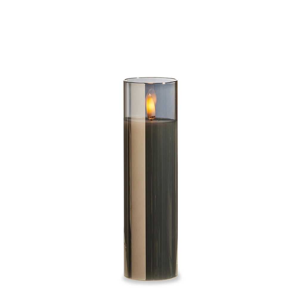 Tall cylindrical candle with a visible flame on a white background