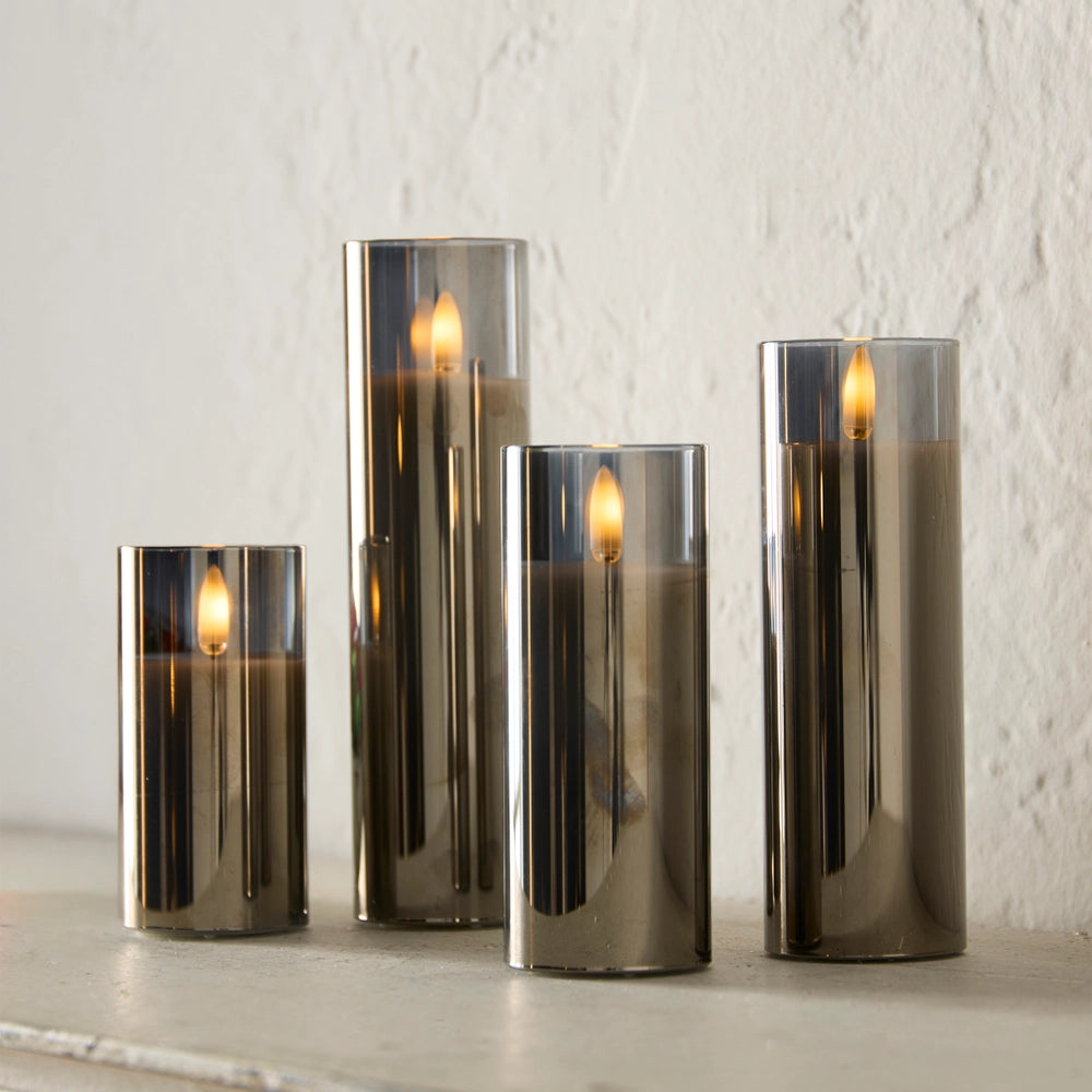 Set of four smoked glass candles with lit candles on a light background