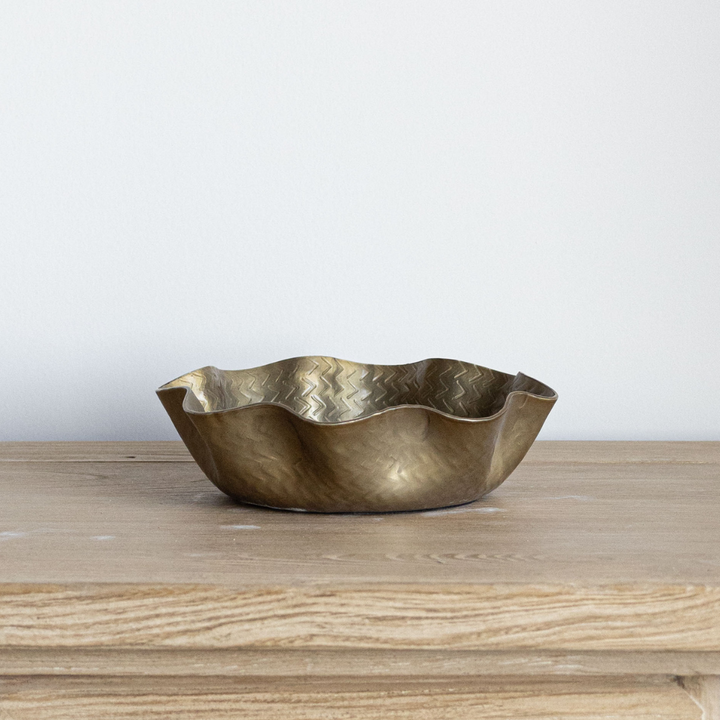 Brass bowl on a wooden surface with a white background