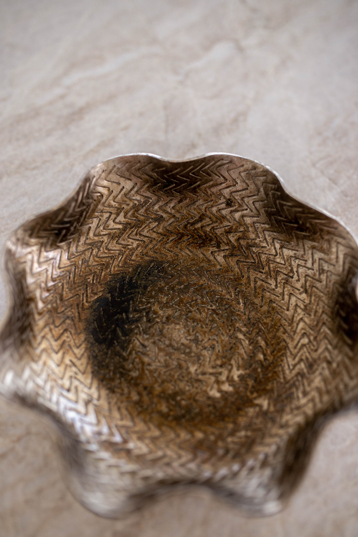 Close-up of a textured metal bowl on a marble surface