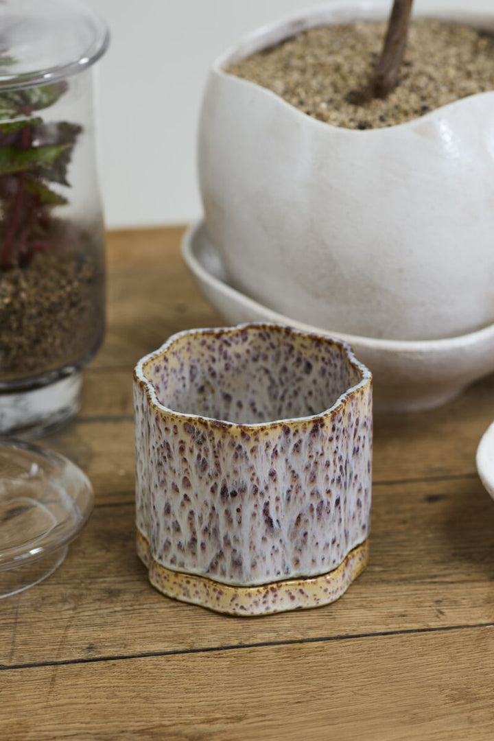 Small ceramic pot with textured surface on a wooden surface