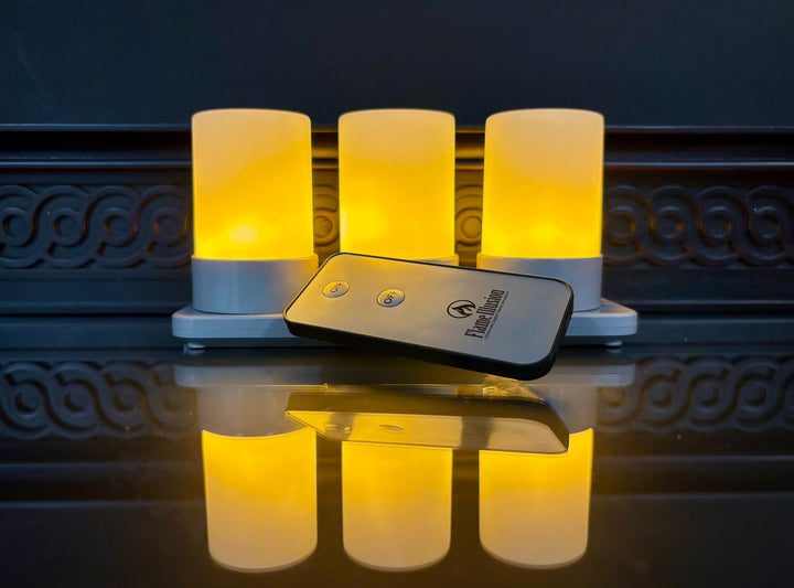 Three glowing cylindrical lights with a remote control on a reflective surface.