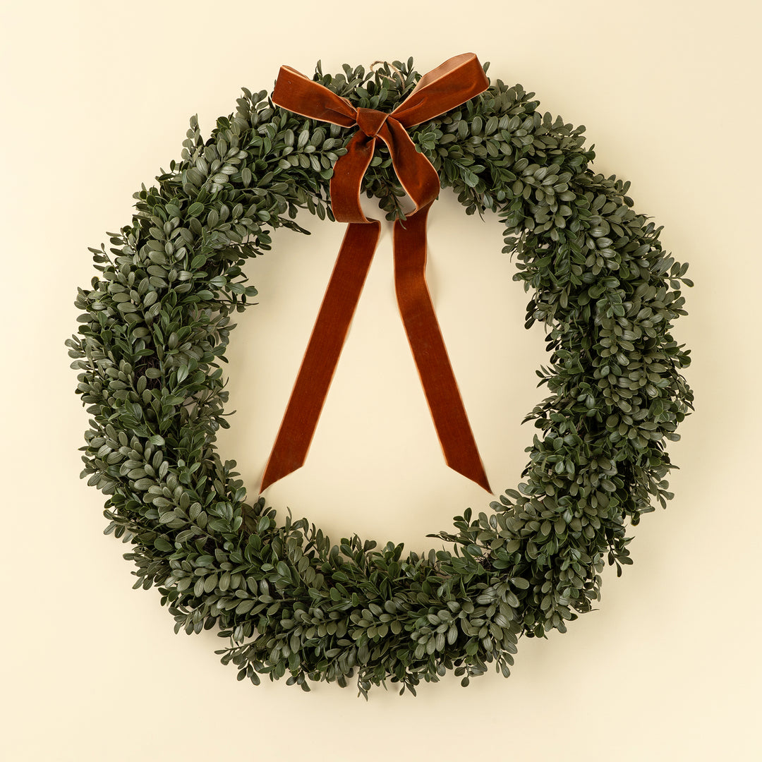 Green wreath with a brown ribbon on a beige background