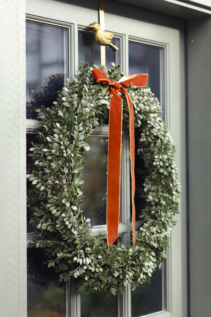 Green wreath with an orange ribbon on a door