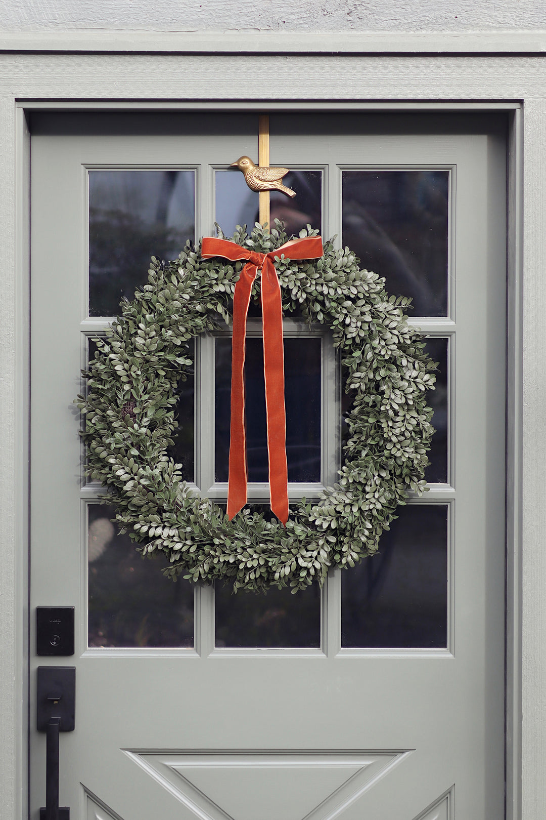 Green wreath with an orange ribbon on a gray door
