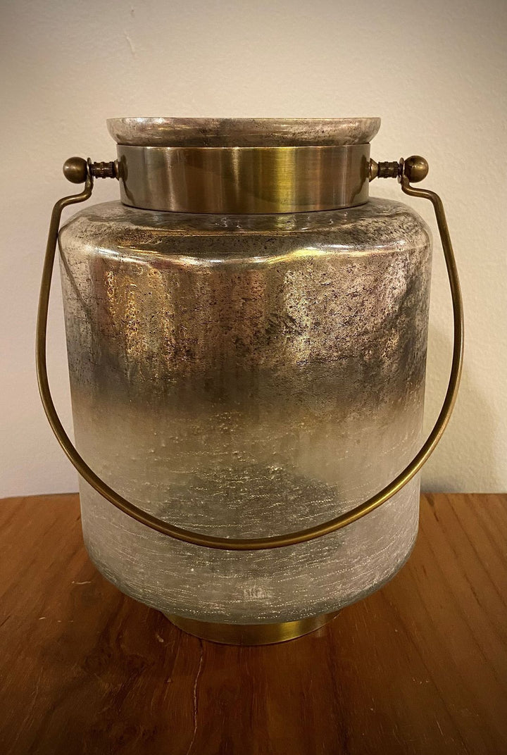 Vintage-style metal lantern with brass accents on a wooden surface.