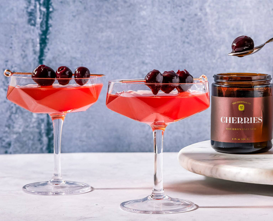 Jar of bourbon-infused cherries with a maroon label on a white background