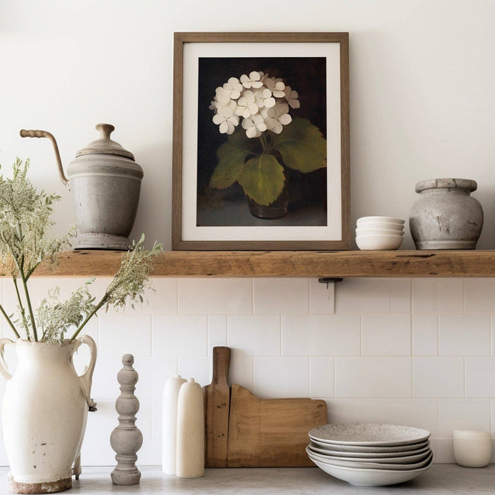 Decorative shelf with a framed floral print, ceramic pots, and kitchen items against a white tiled wall.