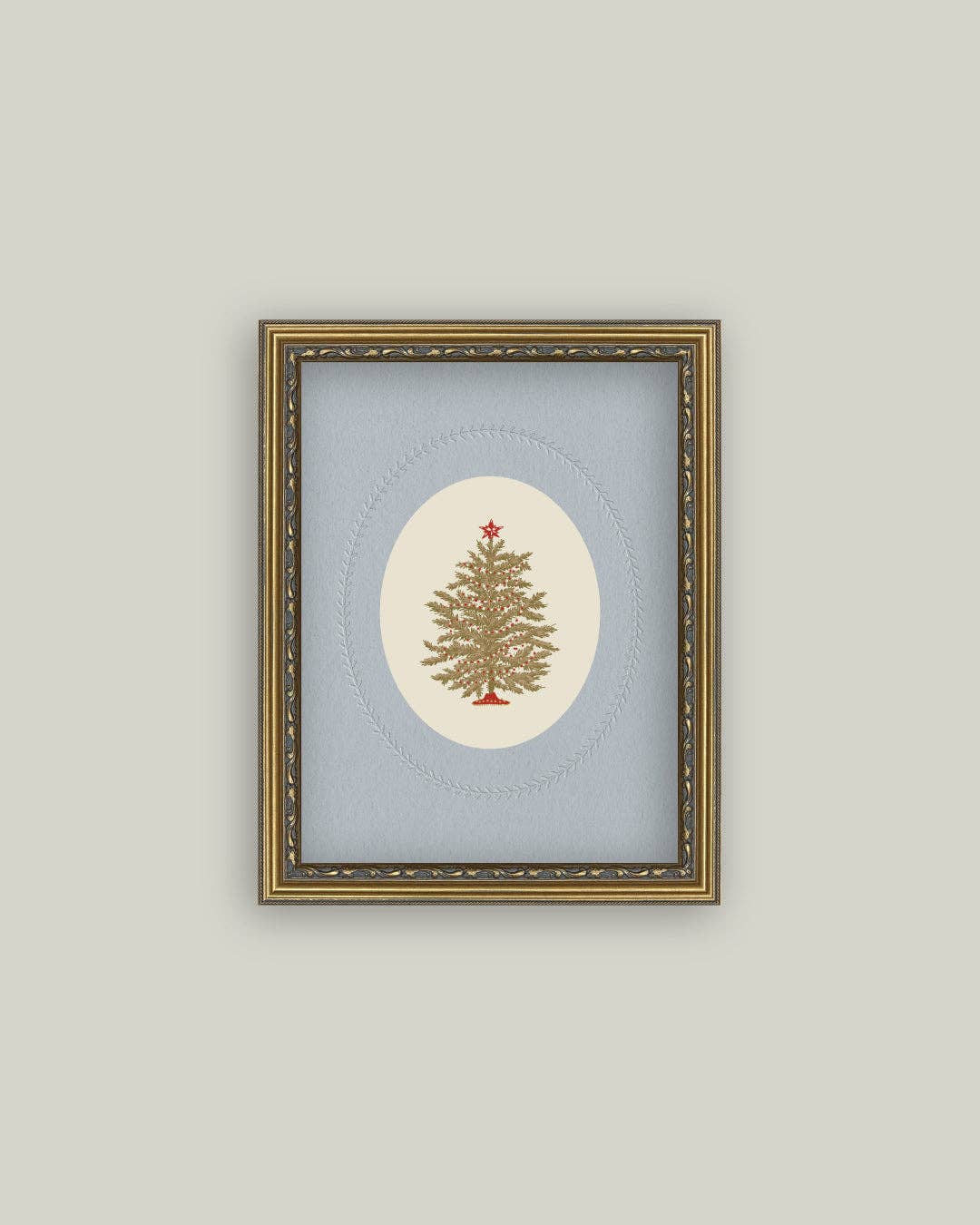 Framed artwork of a Christmas tree on a light blue background with a gold frame.