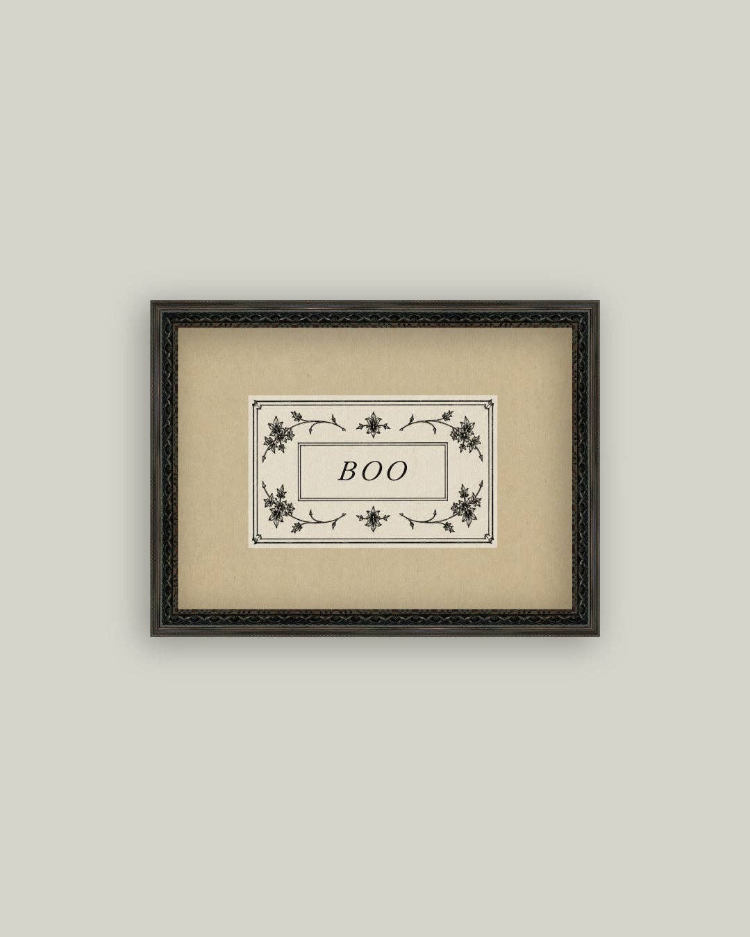 Framed artwork with 'BOO' text on a beige background