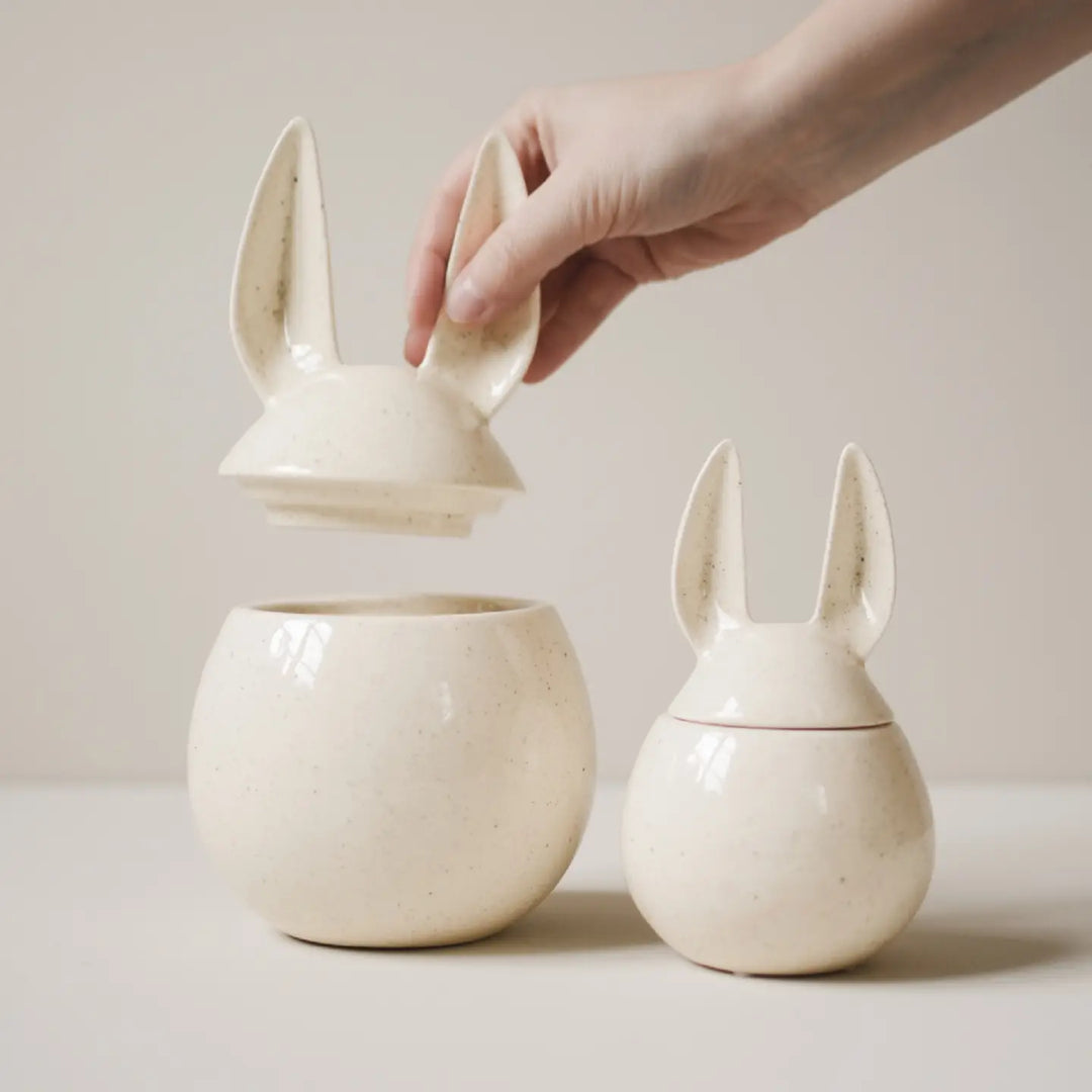 Three ceramic bunny-shaped containers on a light surface with a neutral background