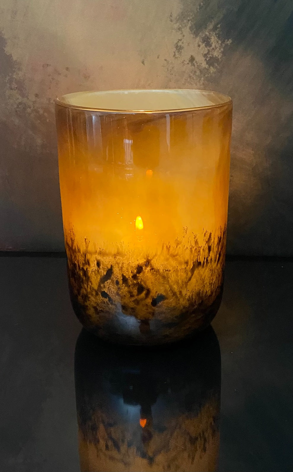 Glass candle holder with a warm glow against a dark background