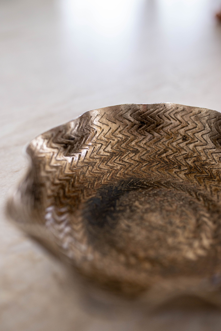 Close-up of a textured bronze bowl on a light background