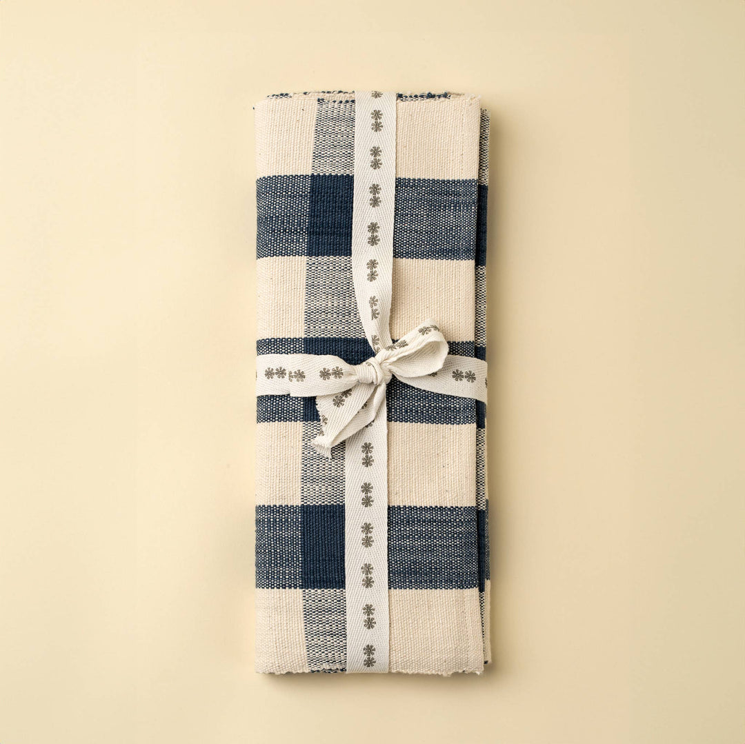 Folded checkered table runner with a white ribbon on a beige background