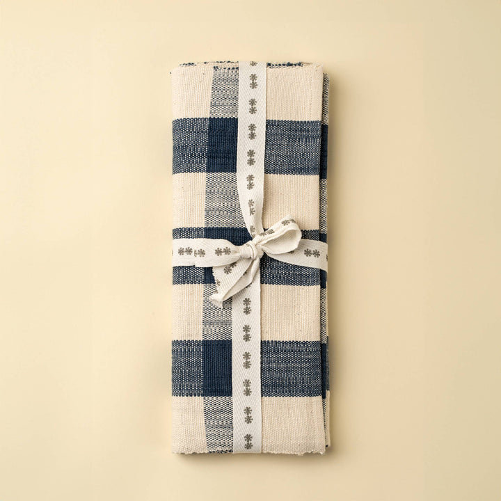 Folded checkered table runner with a white ribbon on a beige background