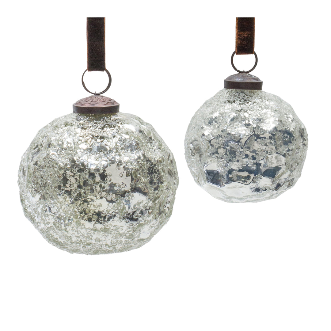 Two silver glass ornaments with a textured surface and metallic caps, suspended by ribbons.