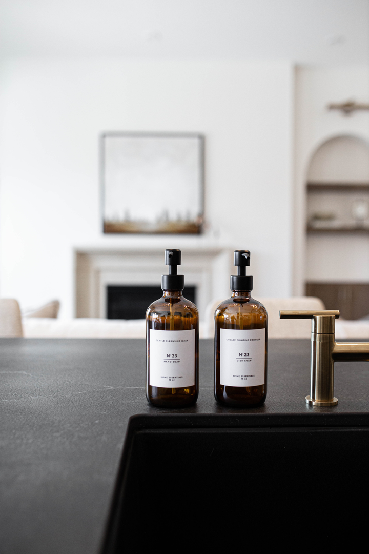Two amber bottles with labels on a black countertop in a modern kitchen.