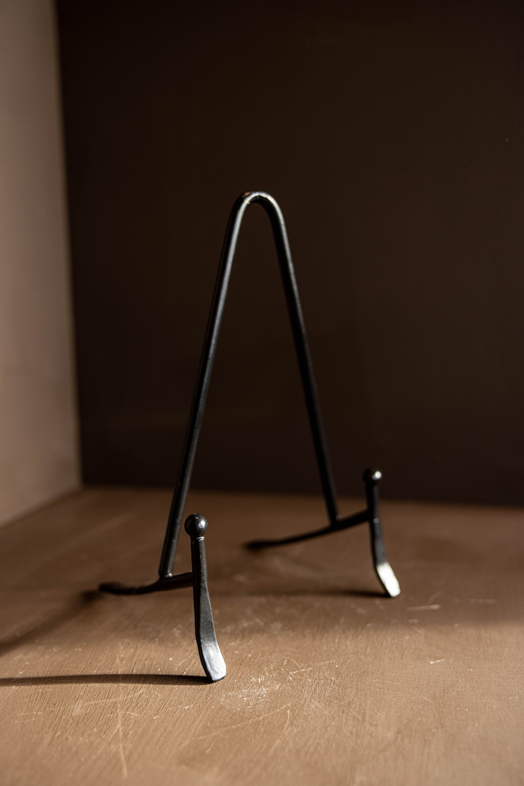 Black metal stand on a brown surface with a dark background