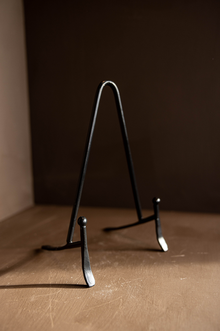 Black metal stand on a brown surface with a dark background