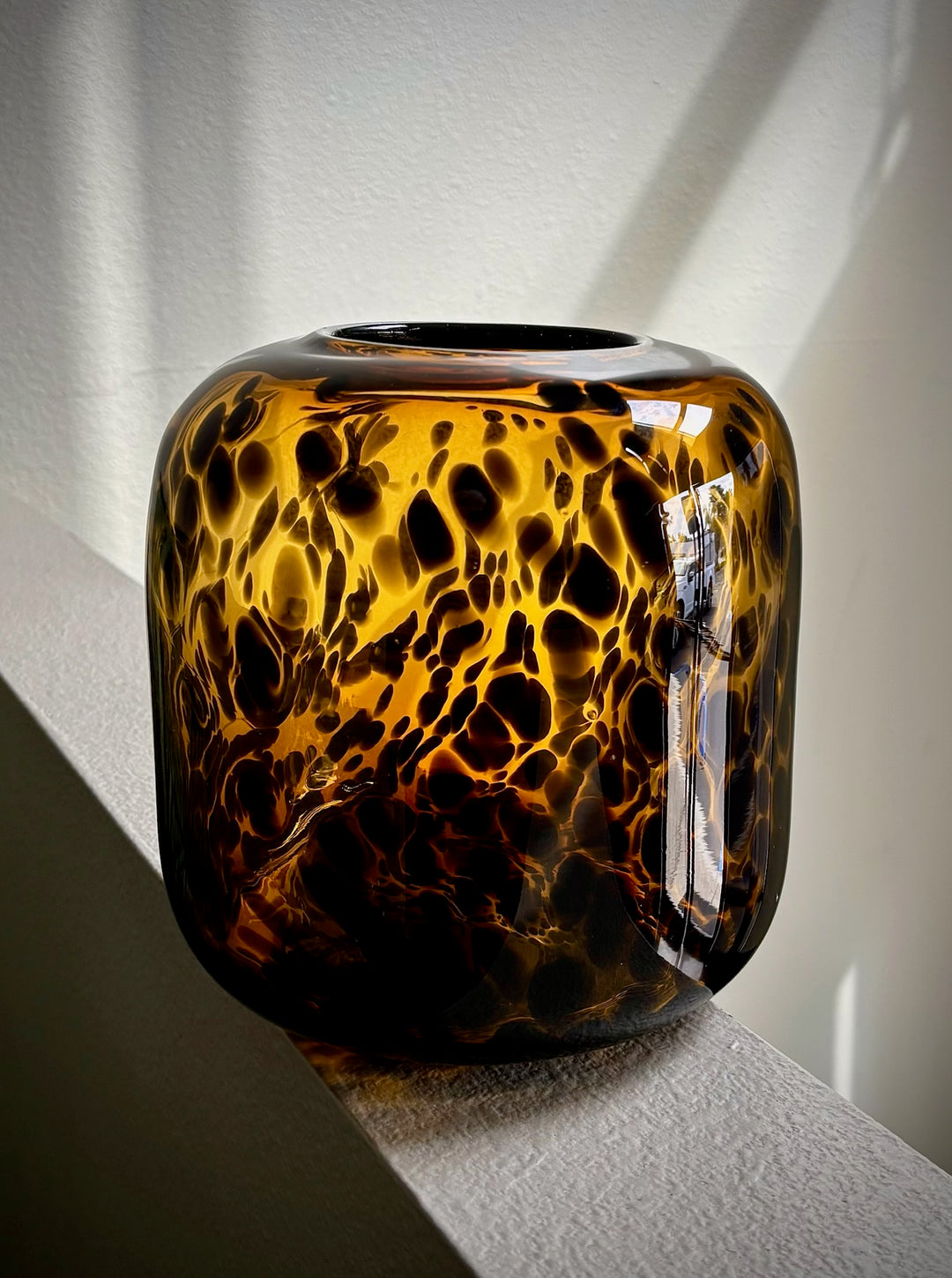 Tortoiseshell patterned vase on a white surface with a light gray background
