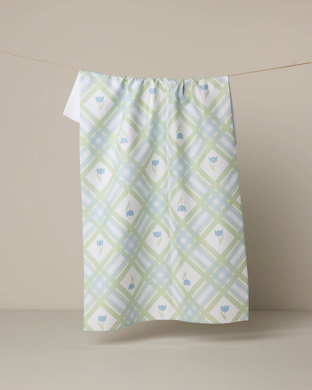 Green and white patterned towel hanging on a line against a beige background