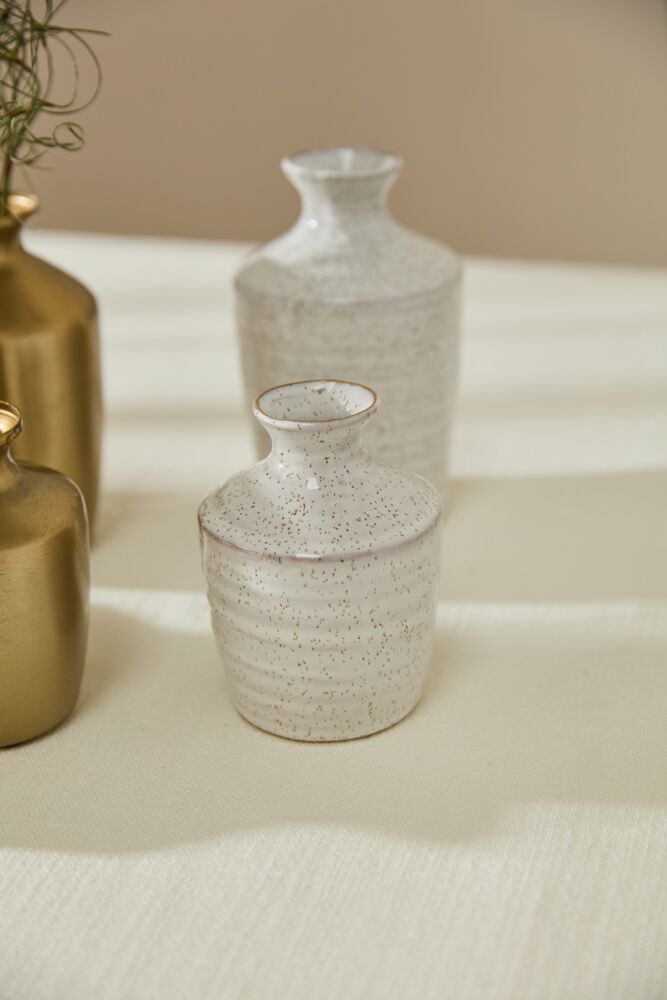 Three ceramic vases on a textured surface with a neutral background