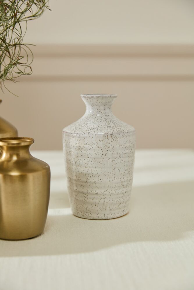 Two vases, one gold and one textured white, on a light surface with a neutral background.
