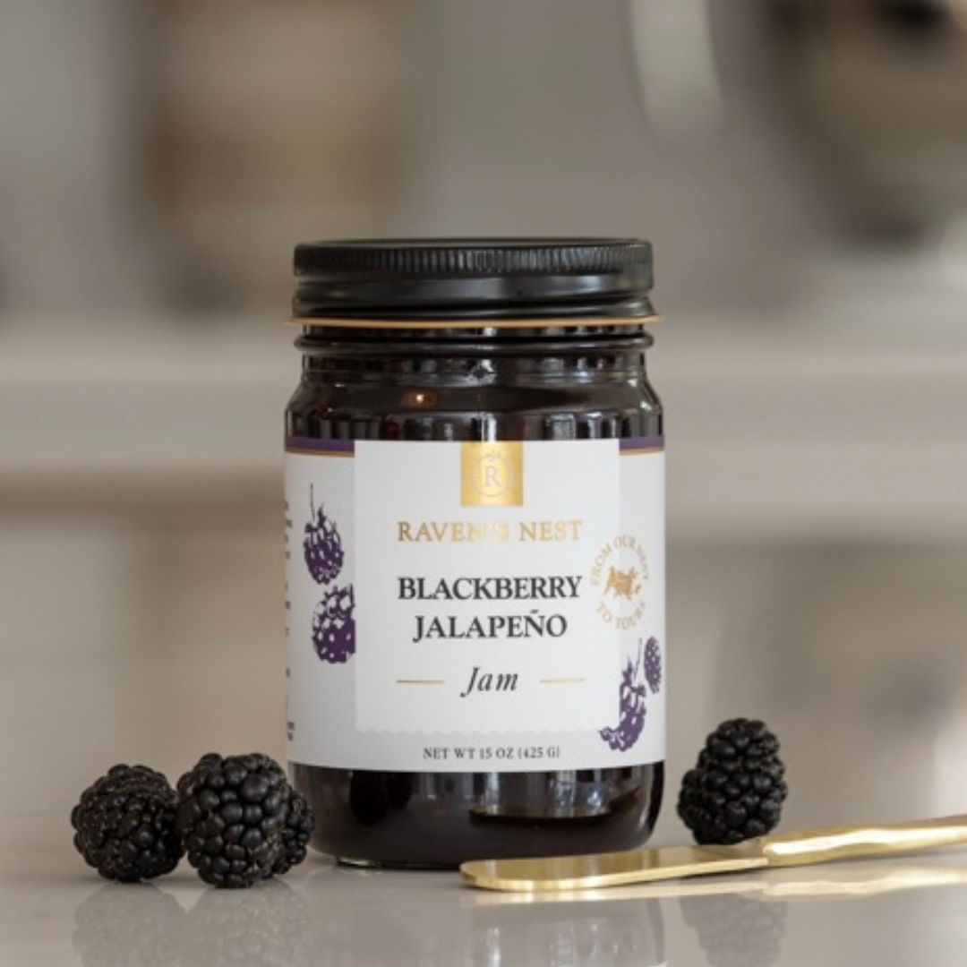 Jar of Blackberry Jalapeño Jam from Raven's Nest with blackberries and a spoon on a neutral background