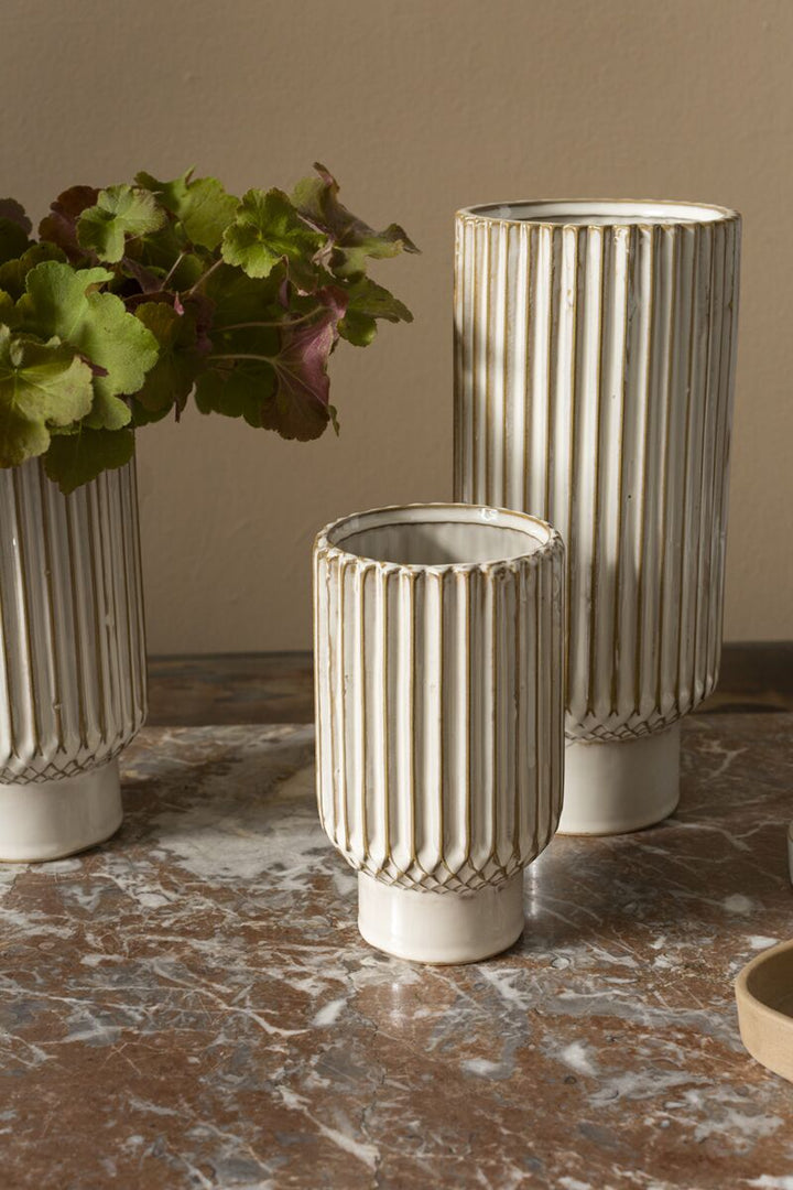 Three textured ceramic vases on a marble surface with a neutral background