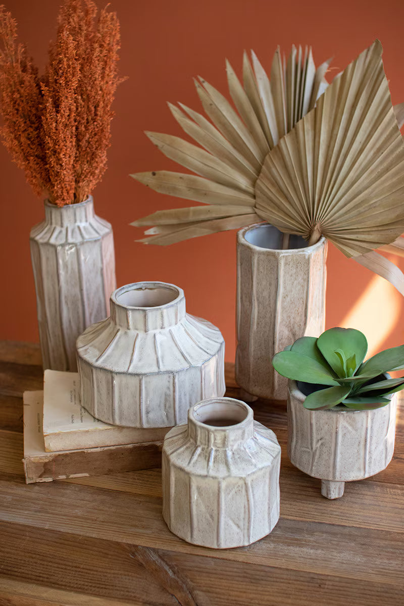 Set of decorative vases and planters on a wooden surface with an orange wall background